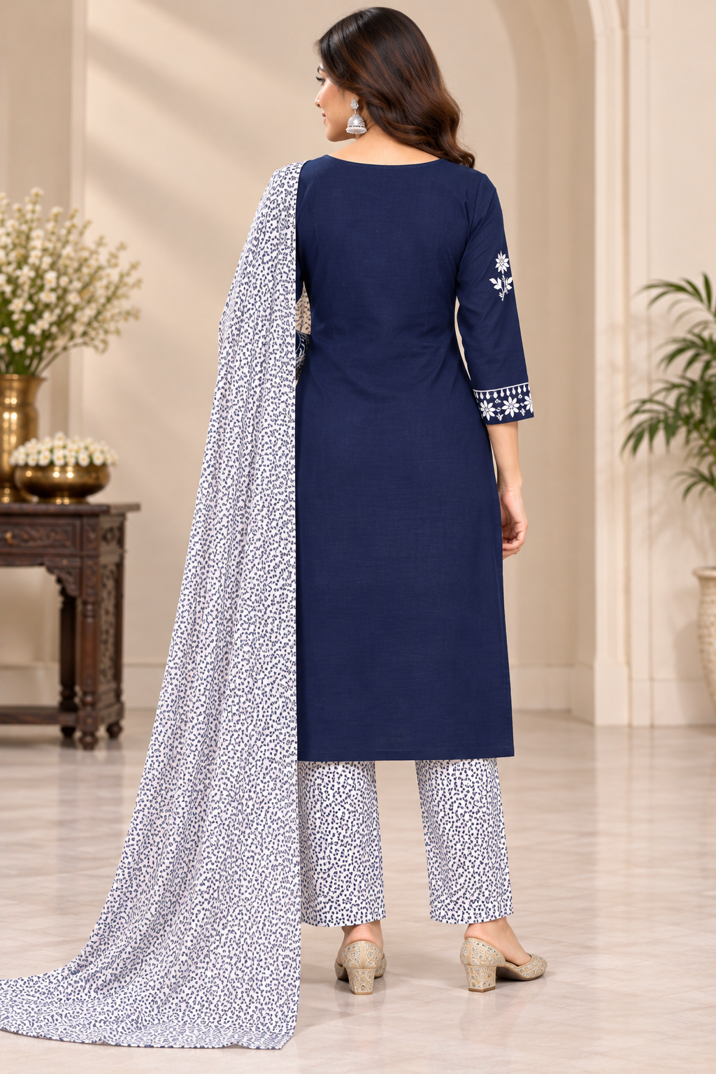 A woman models a navy blue salwar kameez suit with intricate white embroidery, matching patterned trousers, and a coordinating patterned dupatta in an indoor setting.
