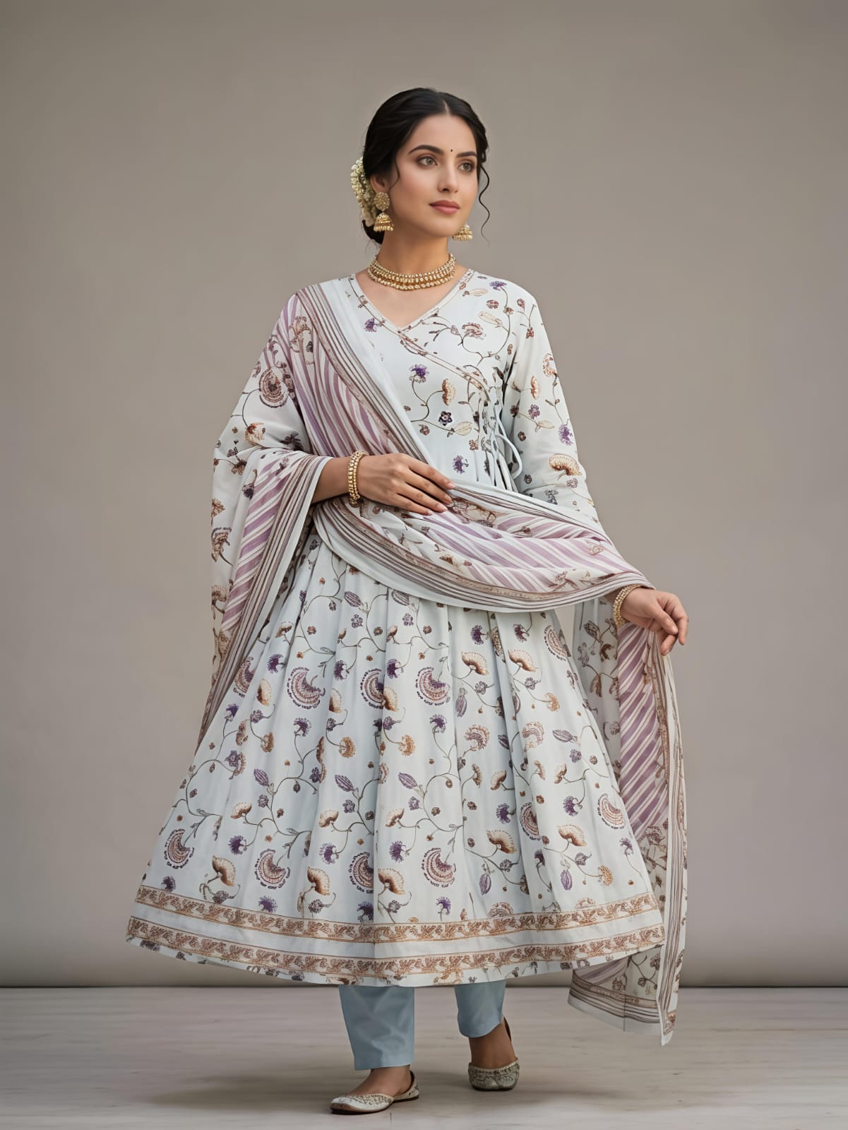 A woman models a traditional Indian outfit consisting of a white printed Anarkali kurta, a matching printed dupatta, and light blue jeans against a neutral studio background.