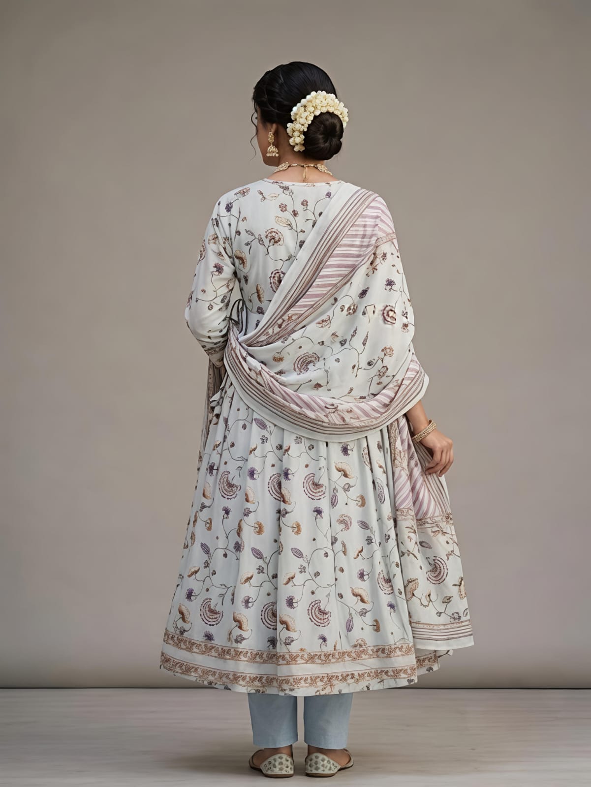 A woman models a traditional Indian outfit consisting of a white printed Anarkali kurta, a matching printed dupatta, and light blue jeans against a neutral studio background.