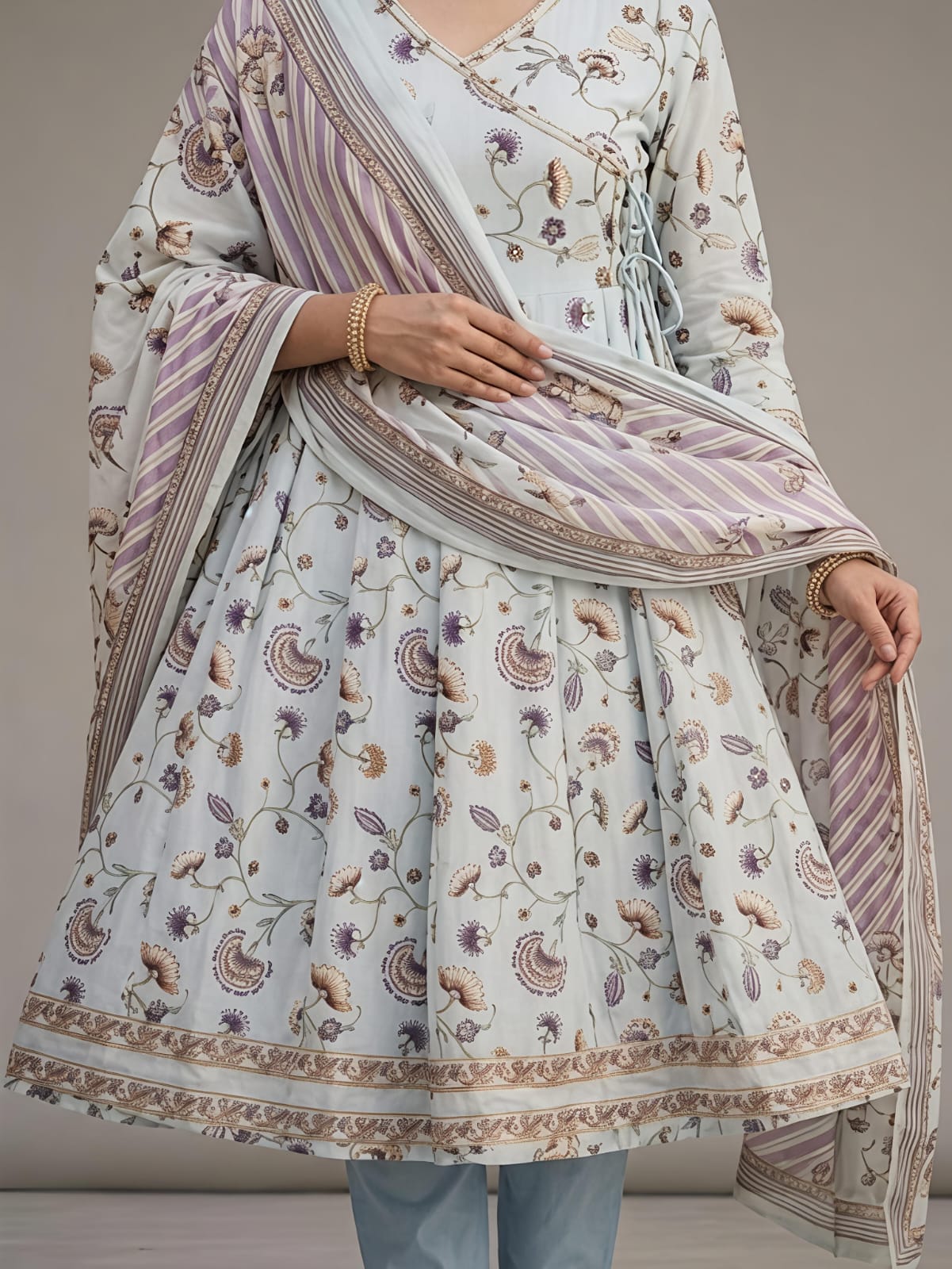 A woman models a traditional Indian outfit consisting of a white printed Anarkali kurta, a matching printed dupatta, and light blue jeans against a neutral studio background.