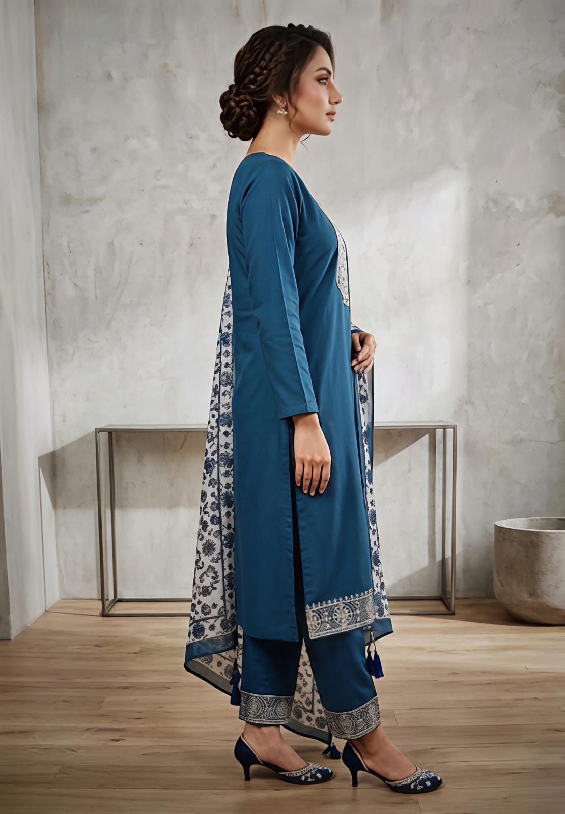 A woman wearing a teal blue kurta with intricate silver embroidery on the chest, paired with a beige and blue floral printed dupatta.